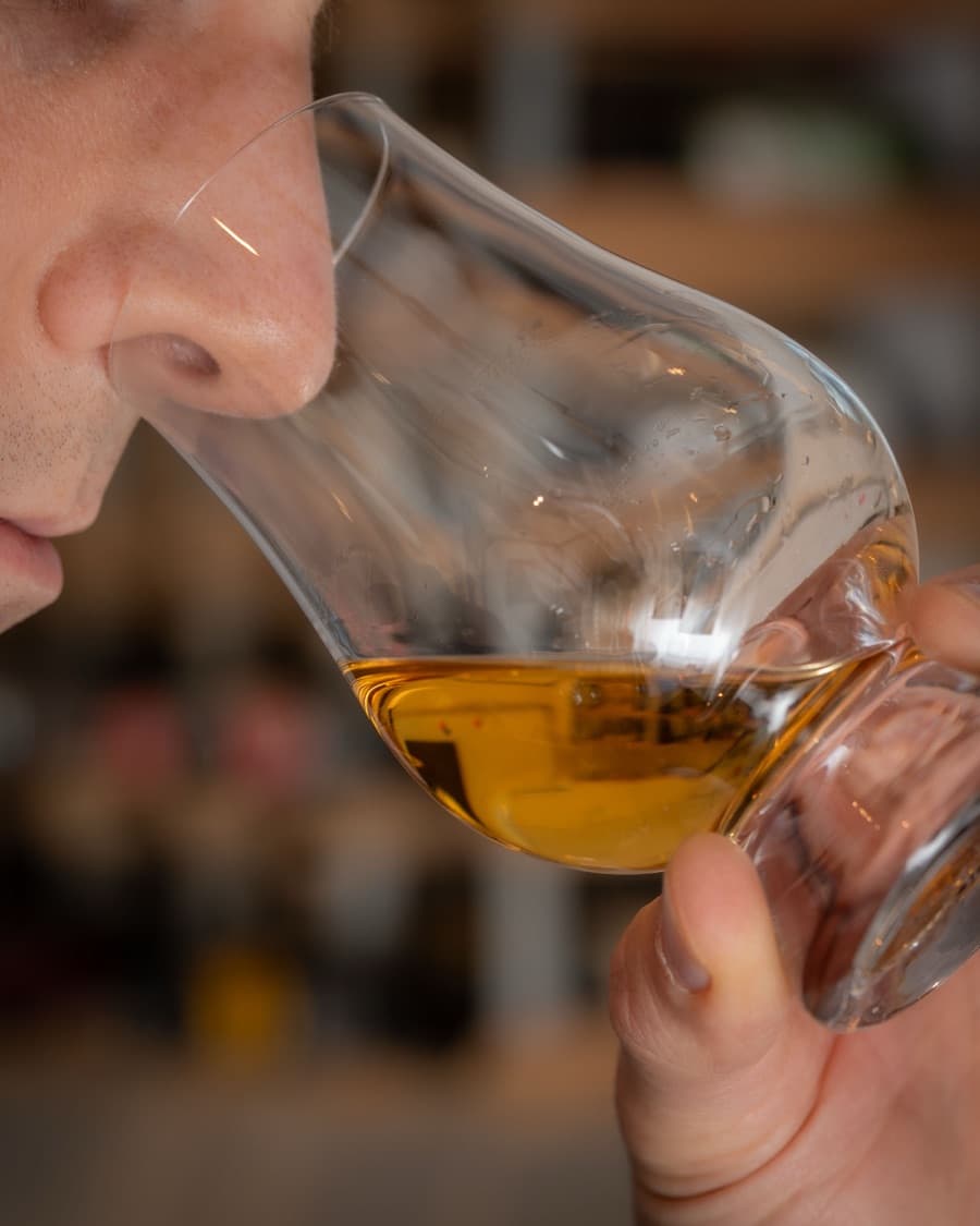 Nosing a whisky, holding the Glencairn glass just below the nose