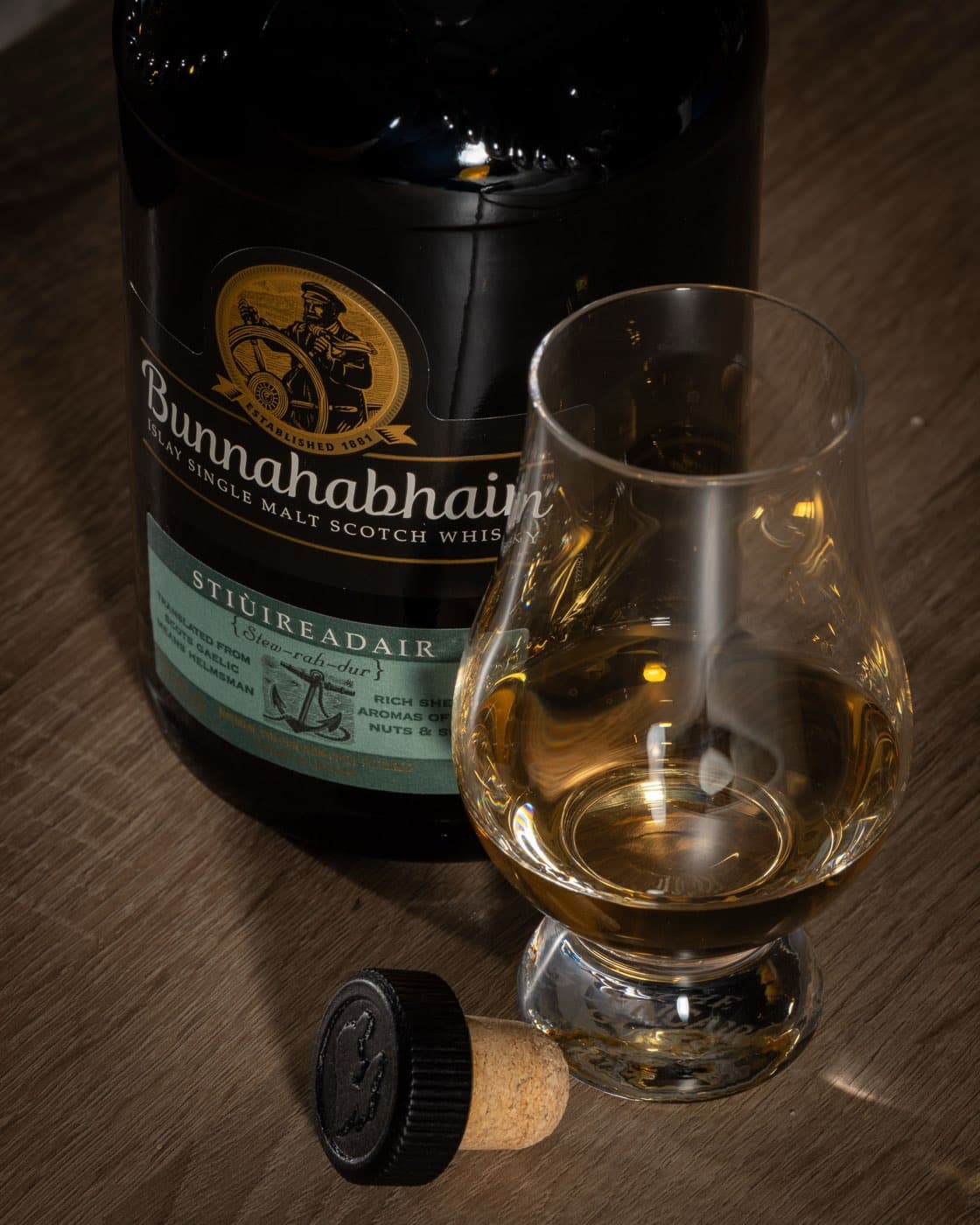 Close-up of the Bunnahabhain Stiùireadair label next to a glass of whisky